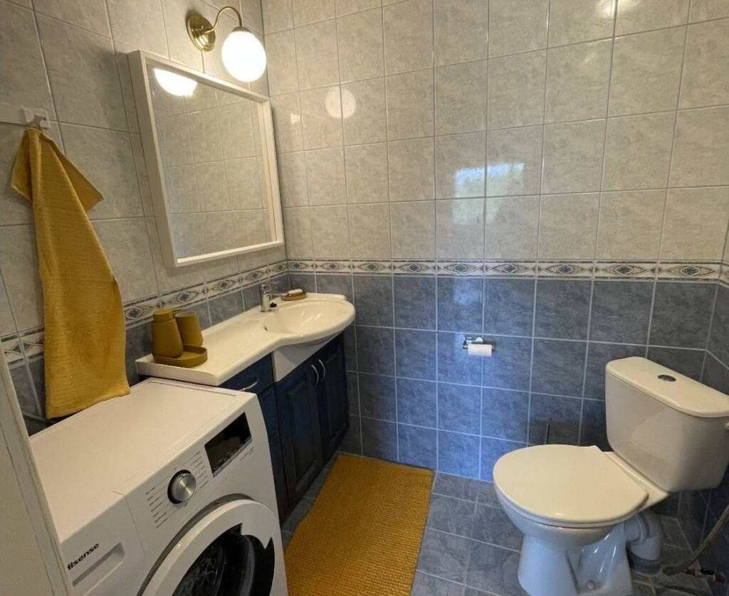 Kaasaegne vannituba pesumasina, kraanikausi ja tualetiga, põrandaküttega