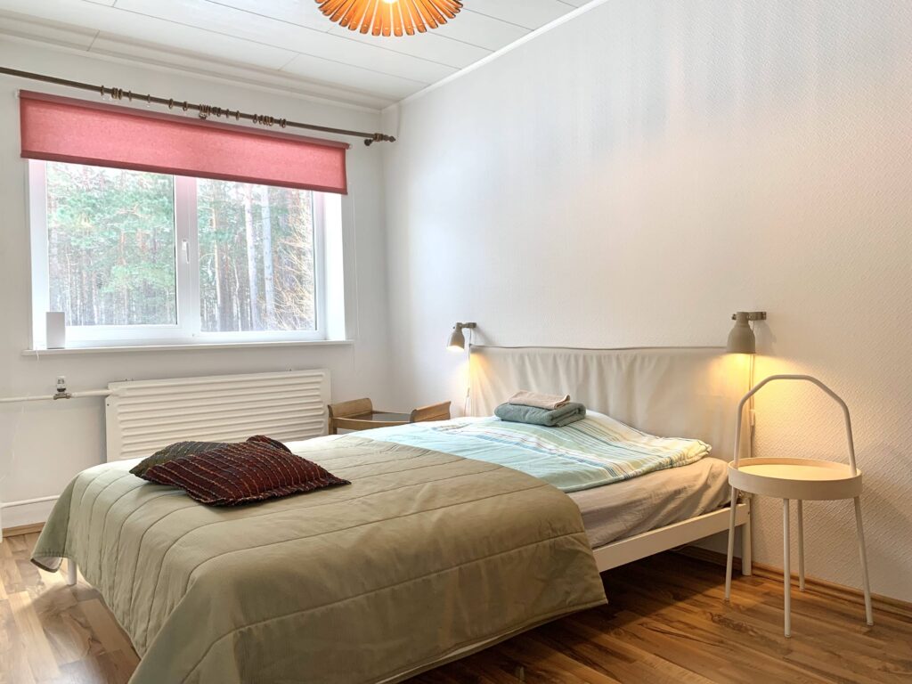 Valgusküllane magamistuba kaheinimesevoodi, lugemislampide ja metsa vaatega